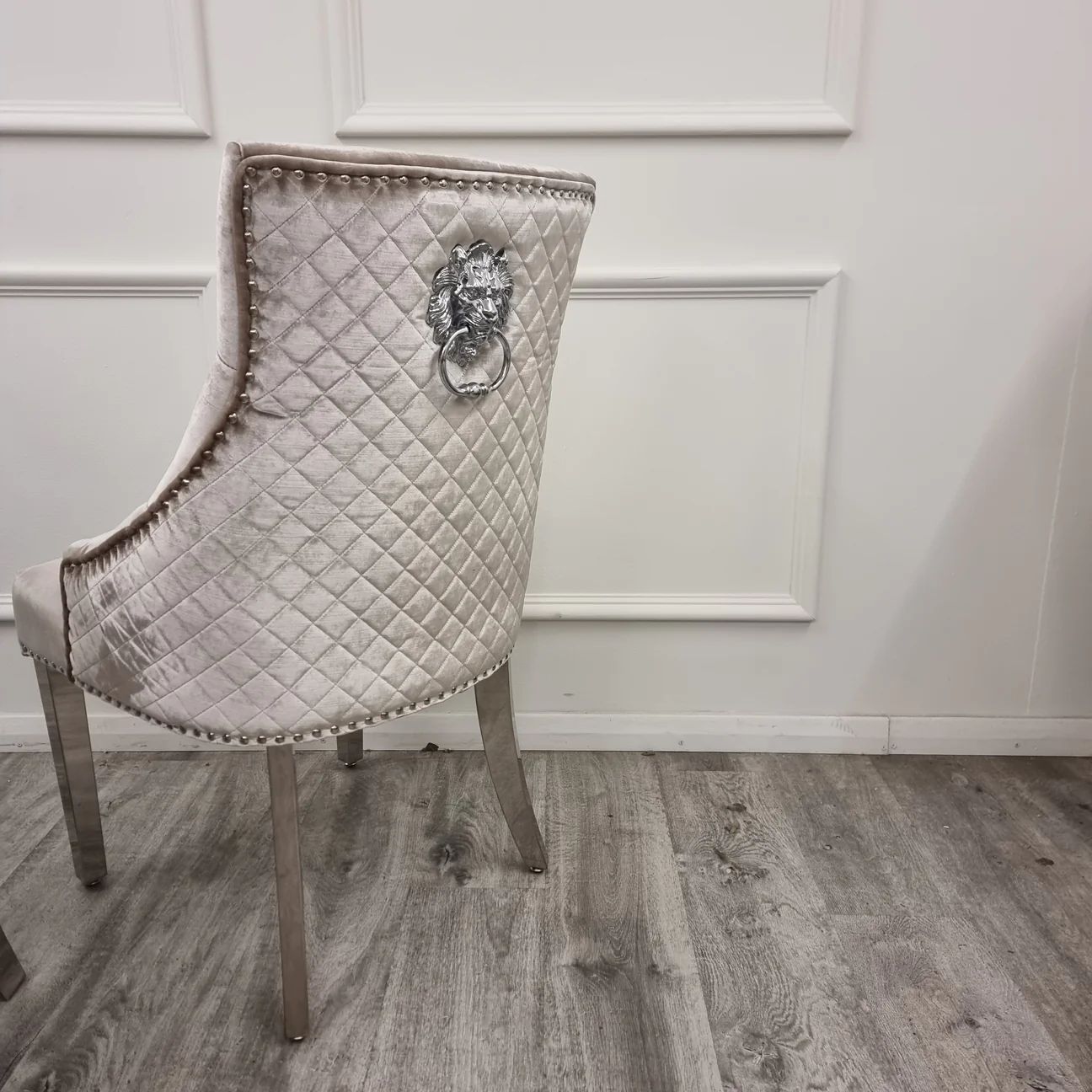 Decorative chair with quilted backrest and lion knocker on a wooden floor.